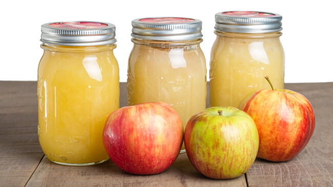 Jars of canned fresh apple sauce with red apples